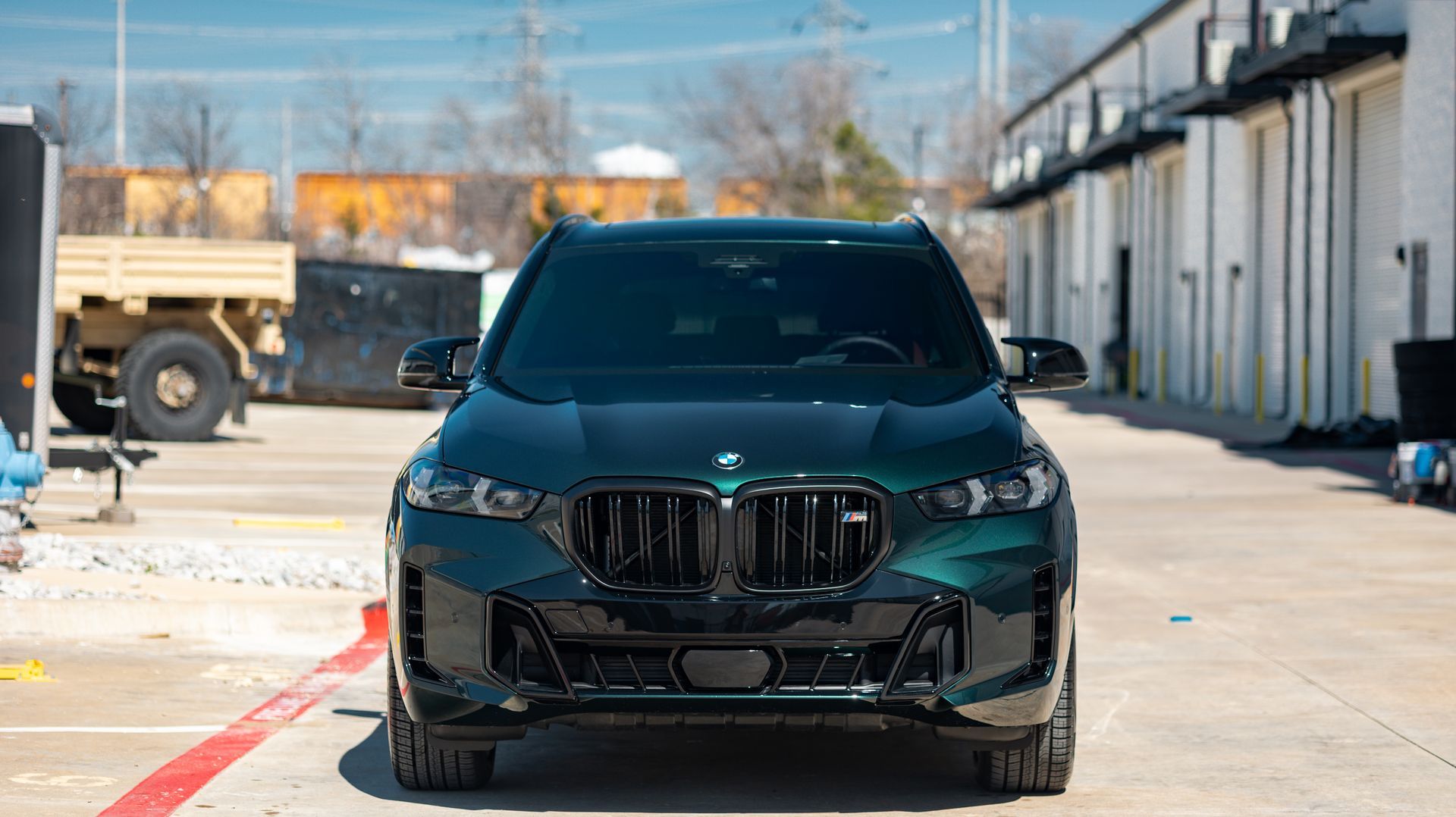 Dark green BMW SUV parked in an industrial lot on a sunny day
