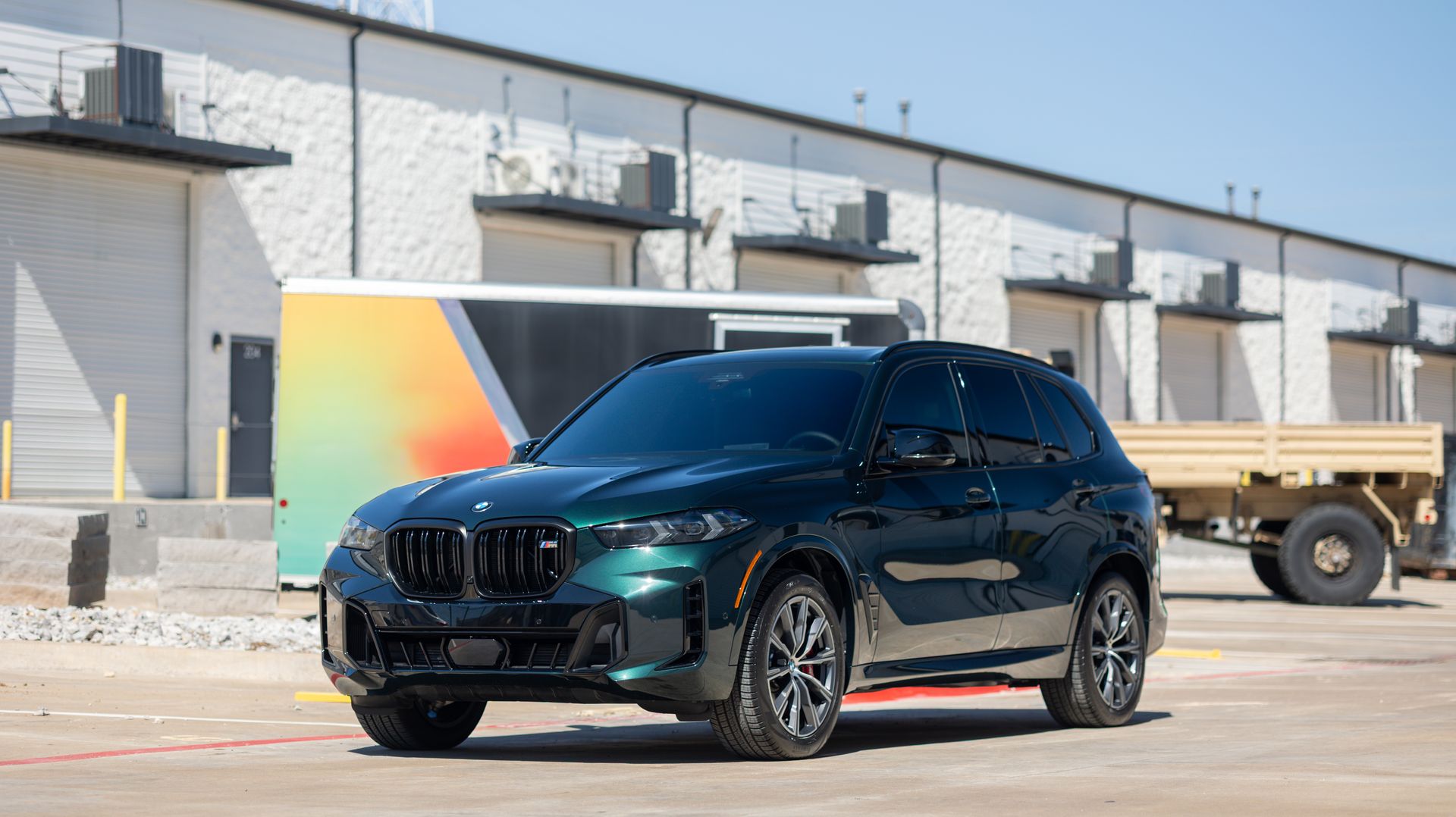 Black BMW SUV parked in front of an industrial building with a colorful mural backdrop