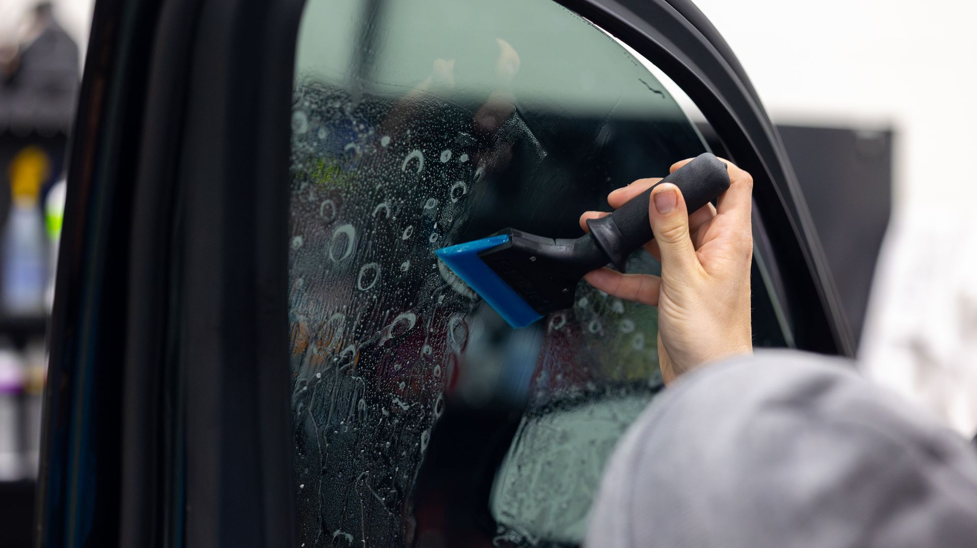 A person uses a smartphone to photograph a shattered car window.