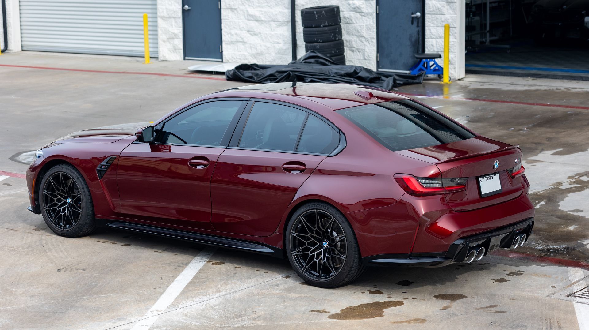 Maroon sedan parked outside a building, viewed from the rear side