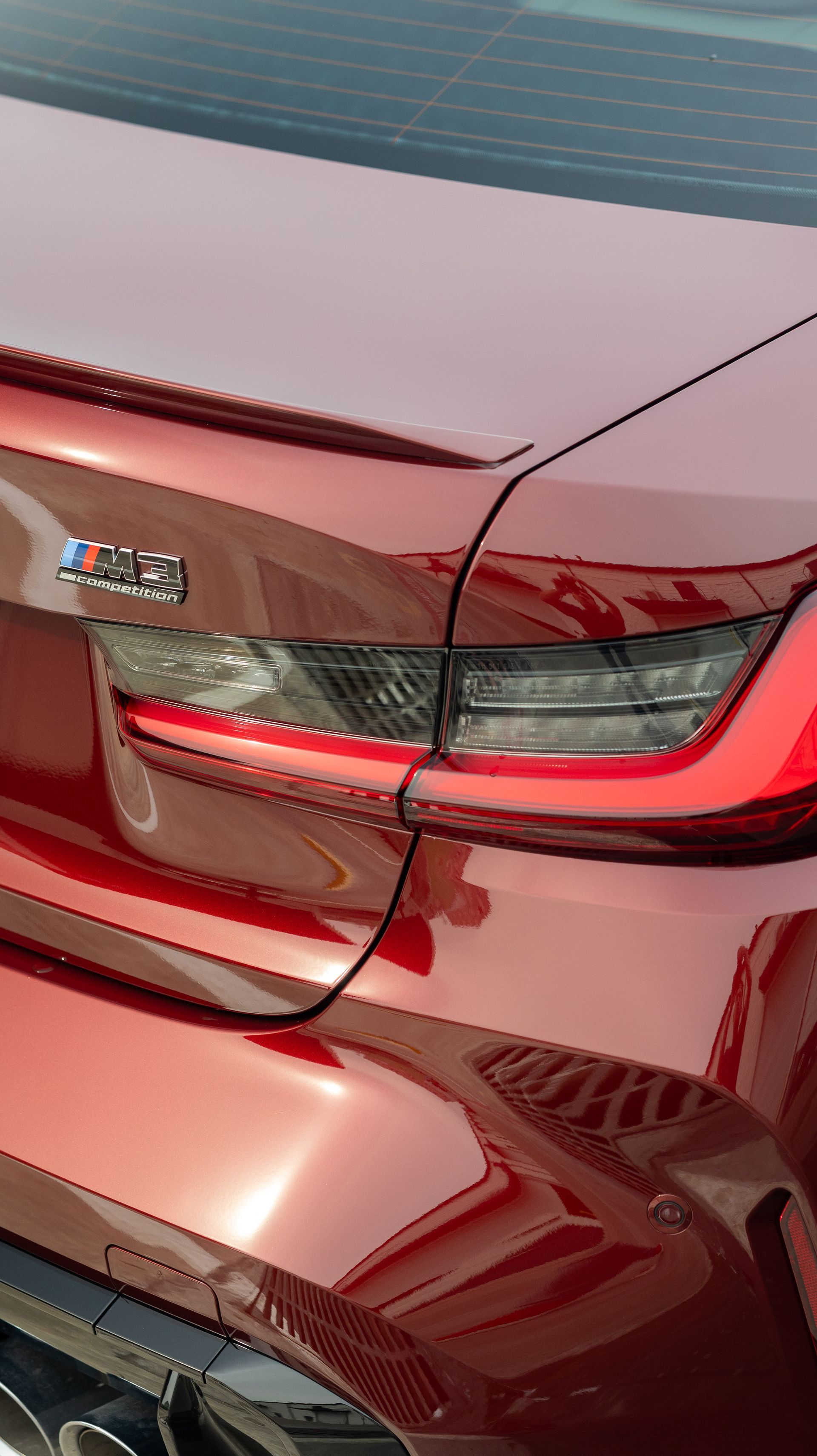 Rear view of a maroon car, close-up of the taillight and trunk seam.