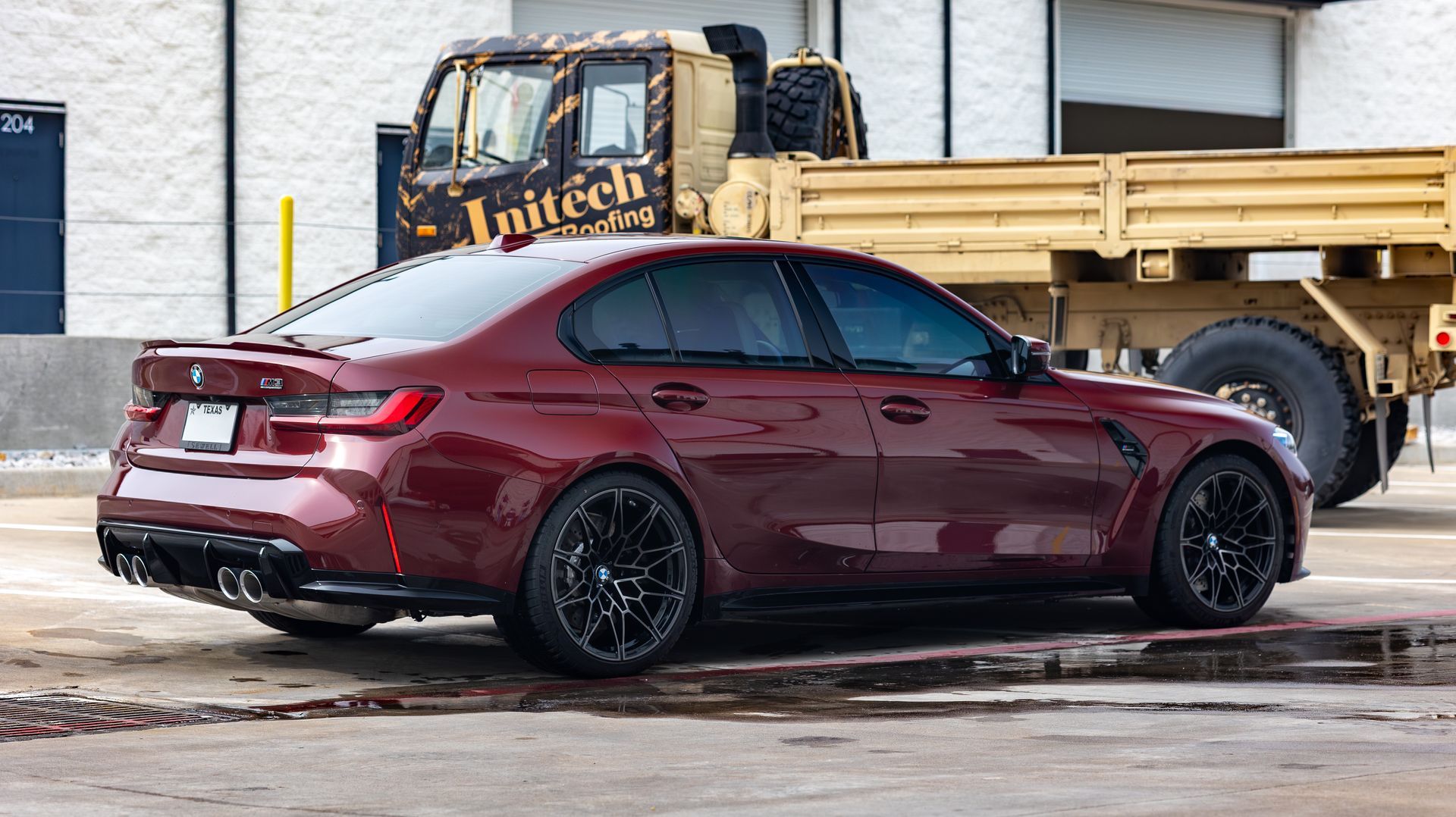 Maroon sedan parked beside a yellow flatbed truck in an industrial lot