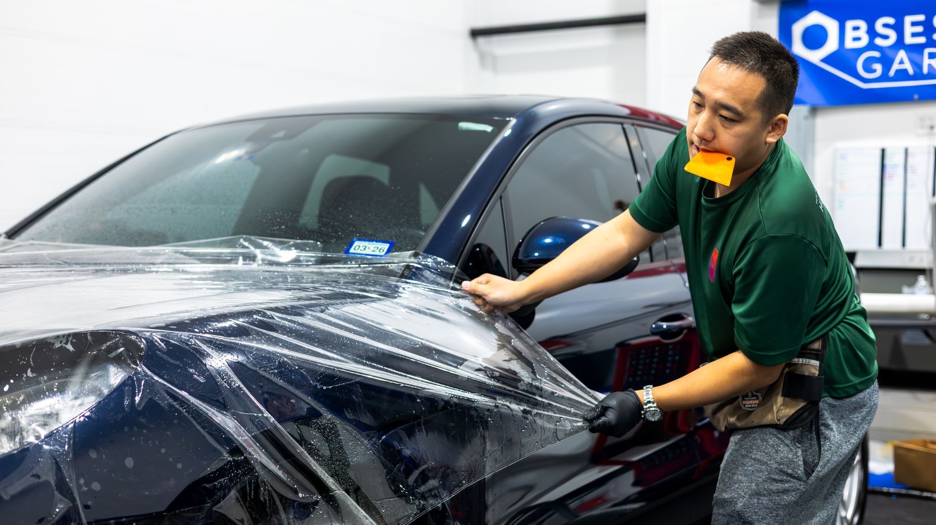 Man washing a black car with a foam sponge in a garage workshop