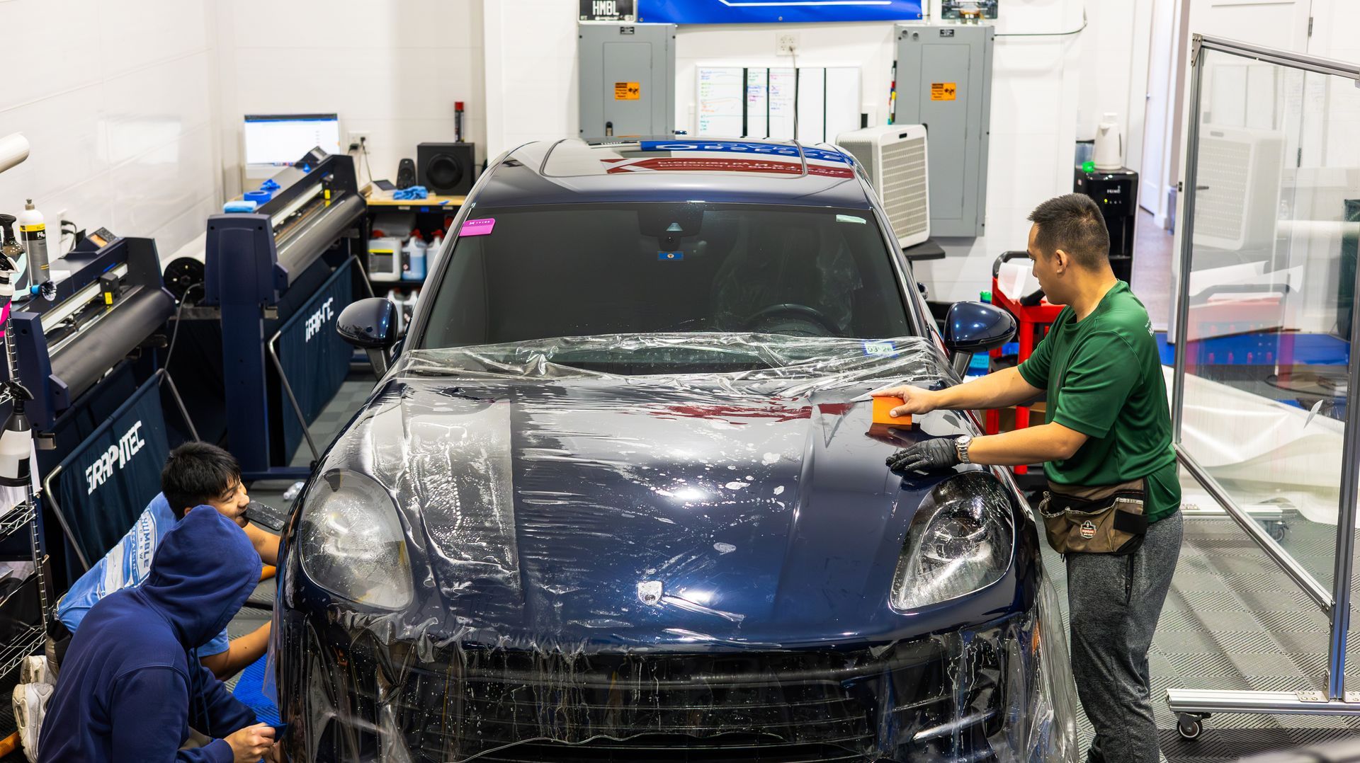 Bulk PPF film draped across the clamshell hood of a Porsche Macan before stretching and laying
