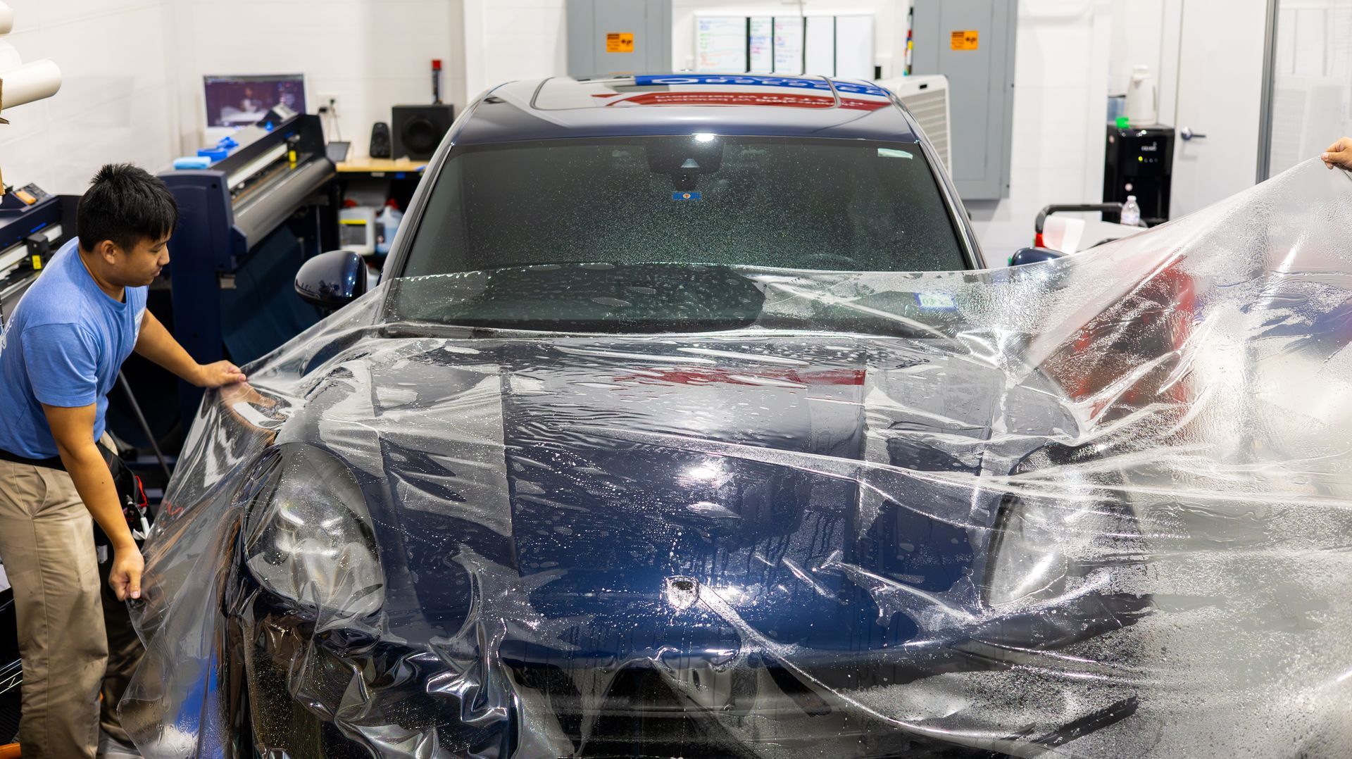 Two workers washing a black SUV in an indoor auto detailing shop