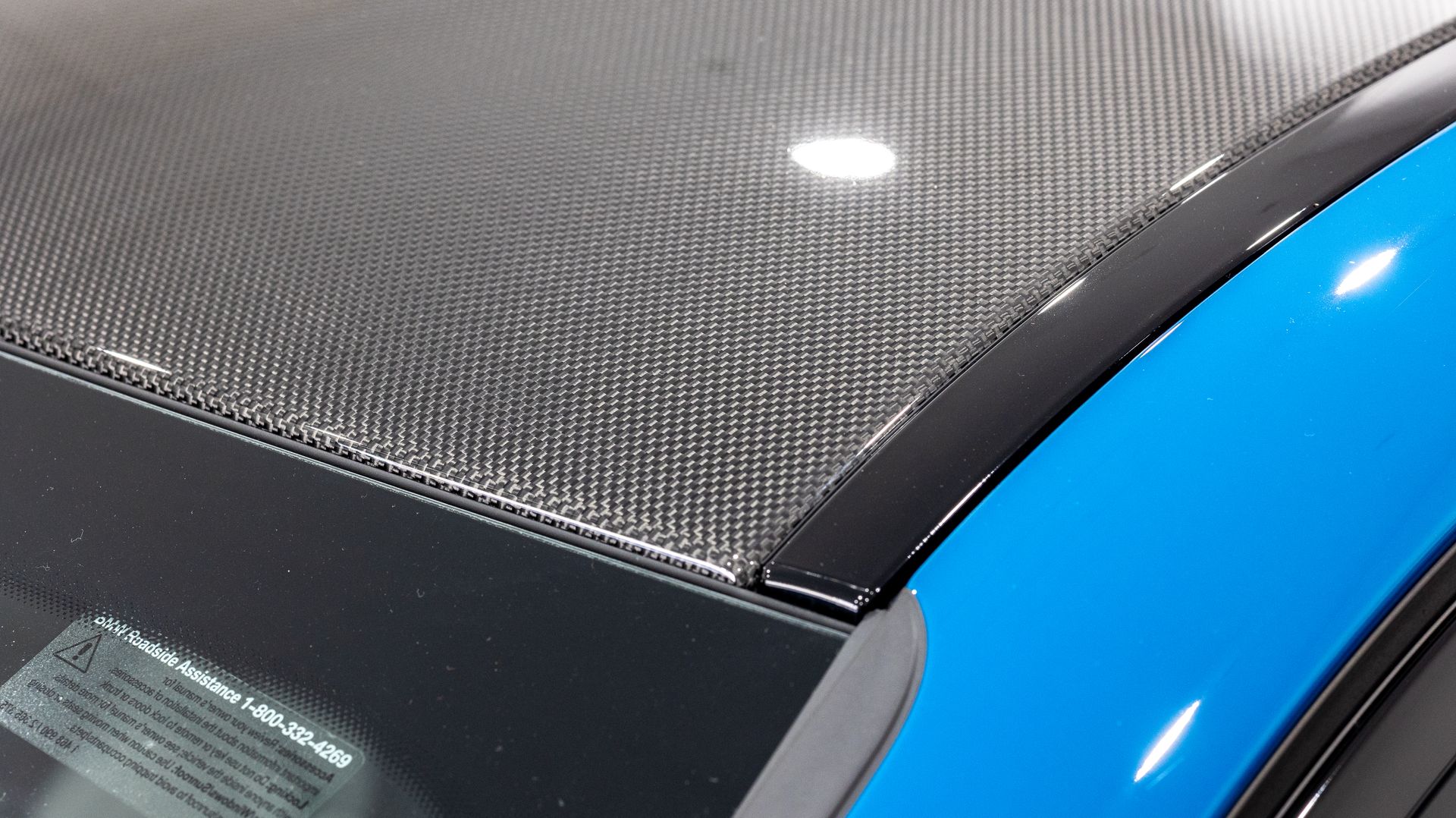 Close-up of a carbon fiber car hood beside a bright blue body panel