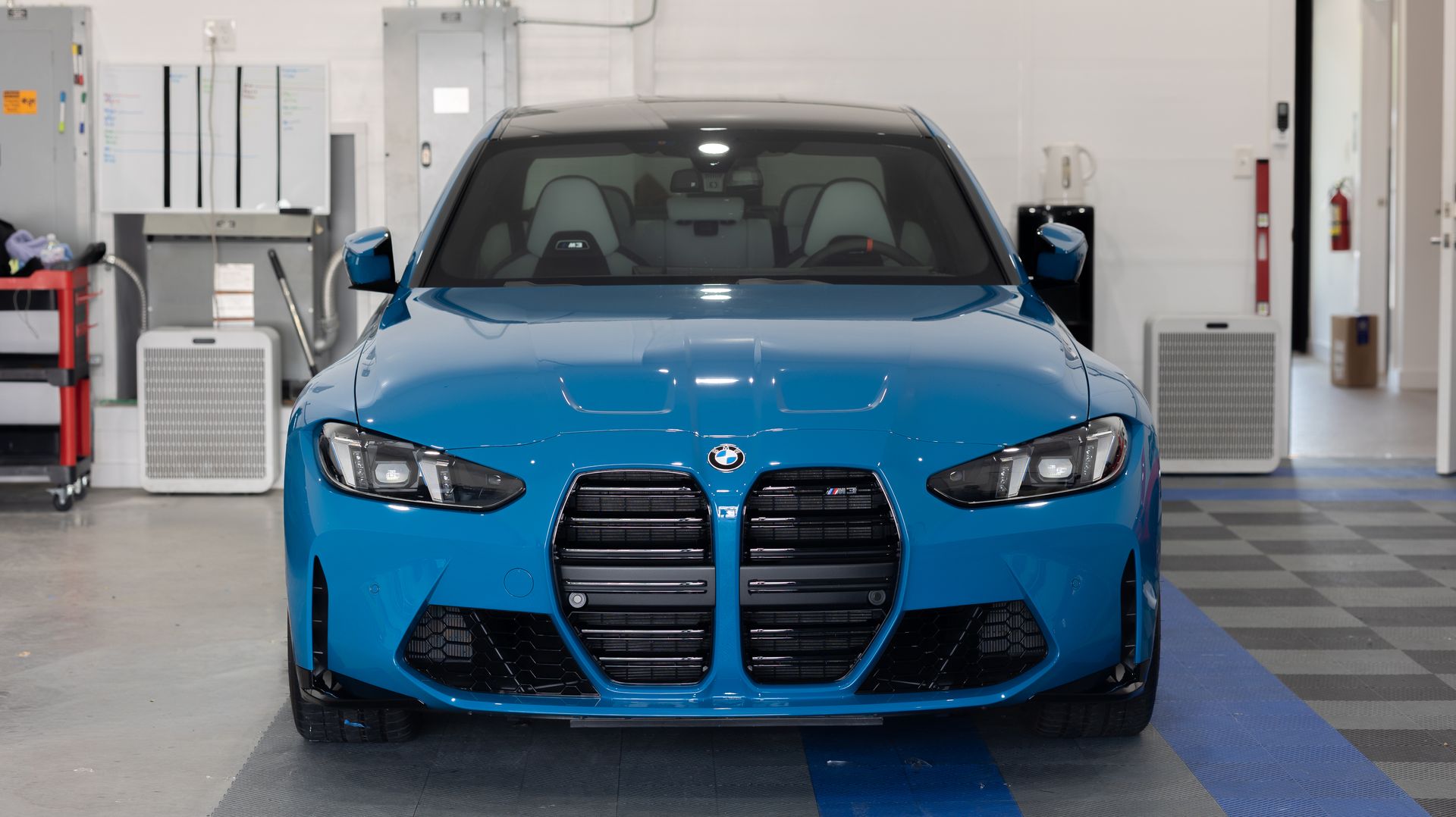 Bright blue BMW sedan parked in a garage, front view