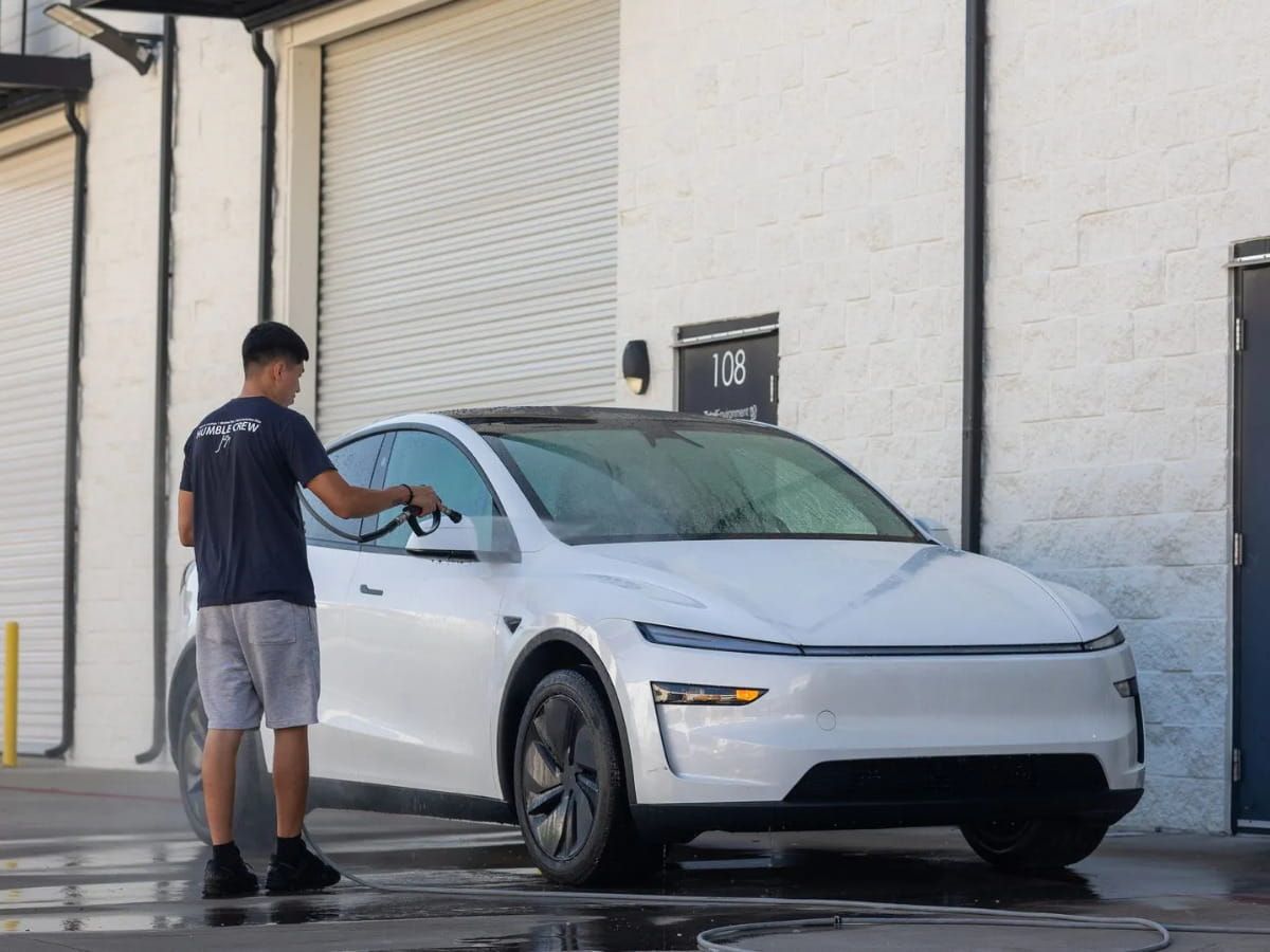 Technician washing a white SUV outside Humble Crew Auto Spa.