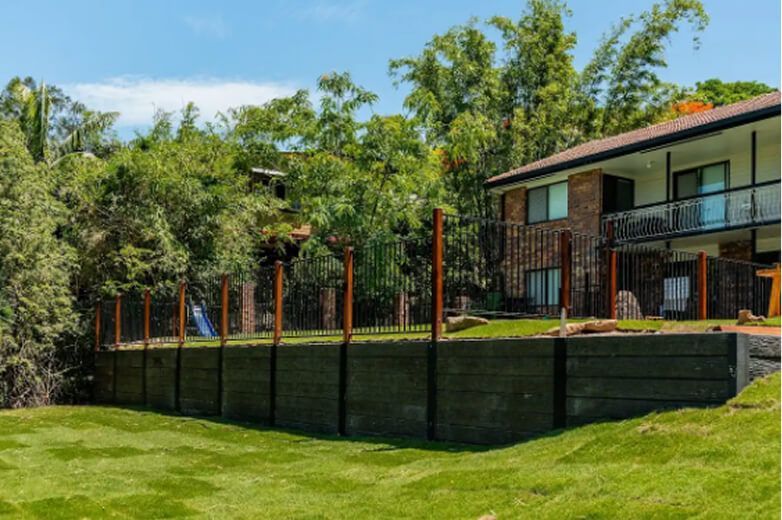 House with black fence and lush green yard on a sunny day