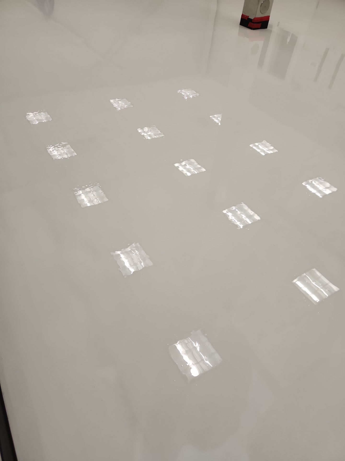 Glossy white floor reflecting ceiling lights, with a small red object at the top edge.