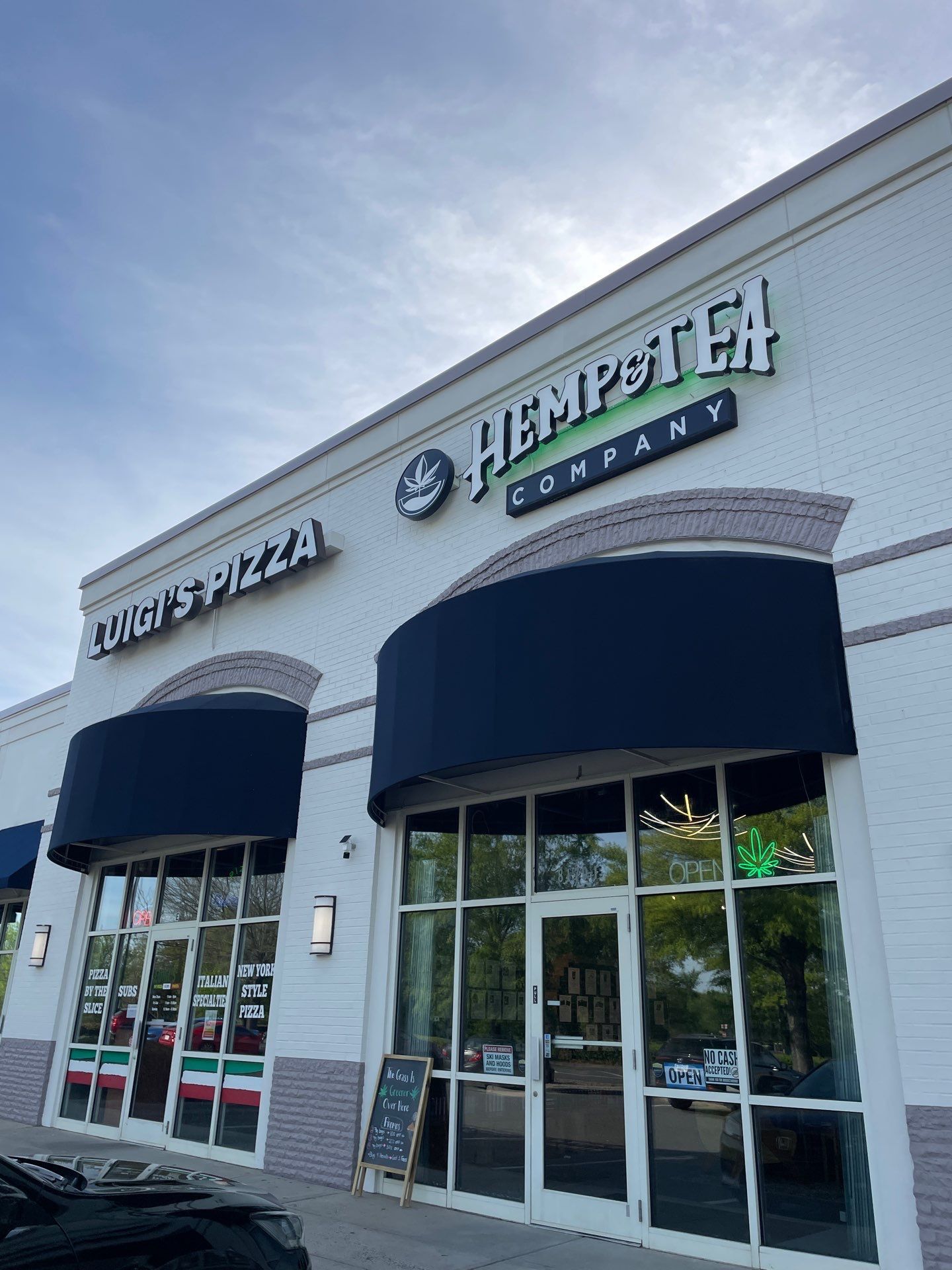 Storefronts for pizza and Hempstead with blue awnings on a shopping center exterior