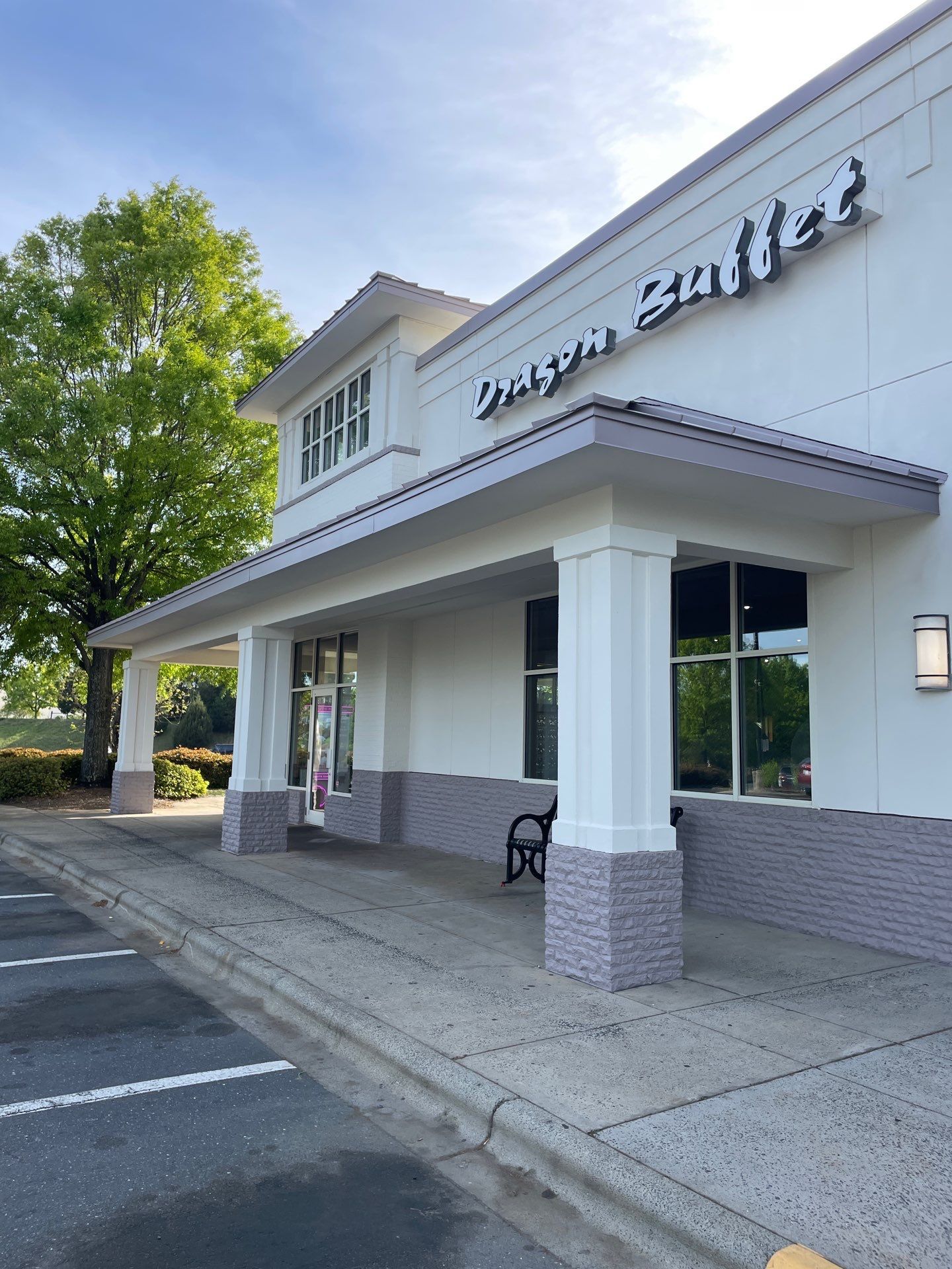 Storefront exterior with white awning, brick columns, and parking lot in front