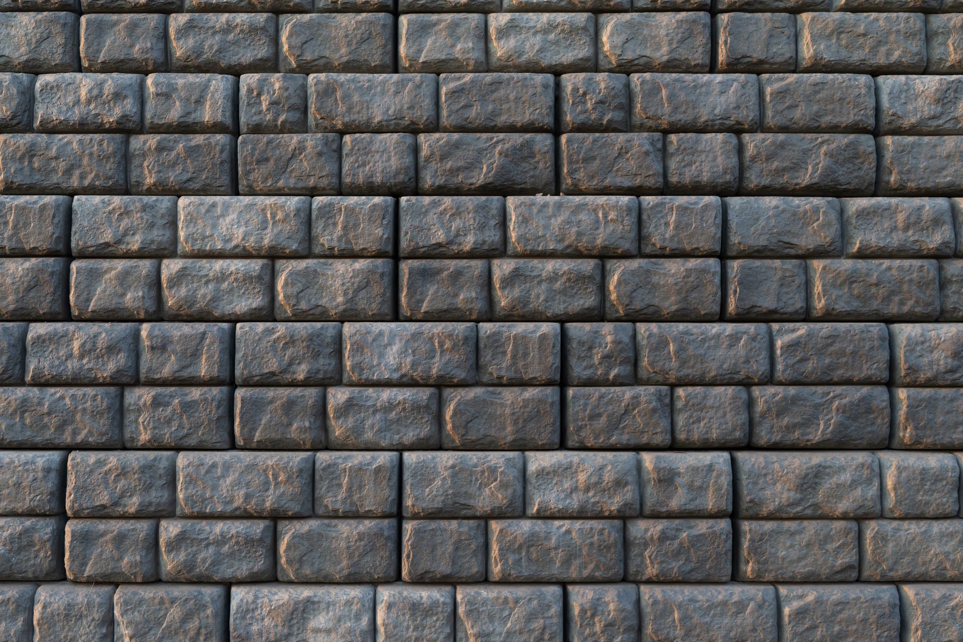 Close-up of a wall made of rectangular, rough-textured dark gray stones arranged in a uniform stacked pattern.