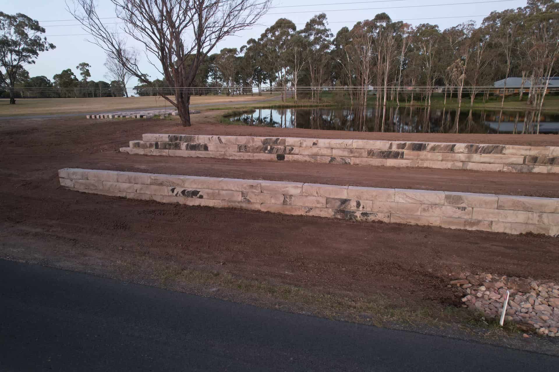 An aerial view of a backyard showing a large rectangular area marked with deep trenches for a residential foundation.