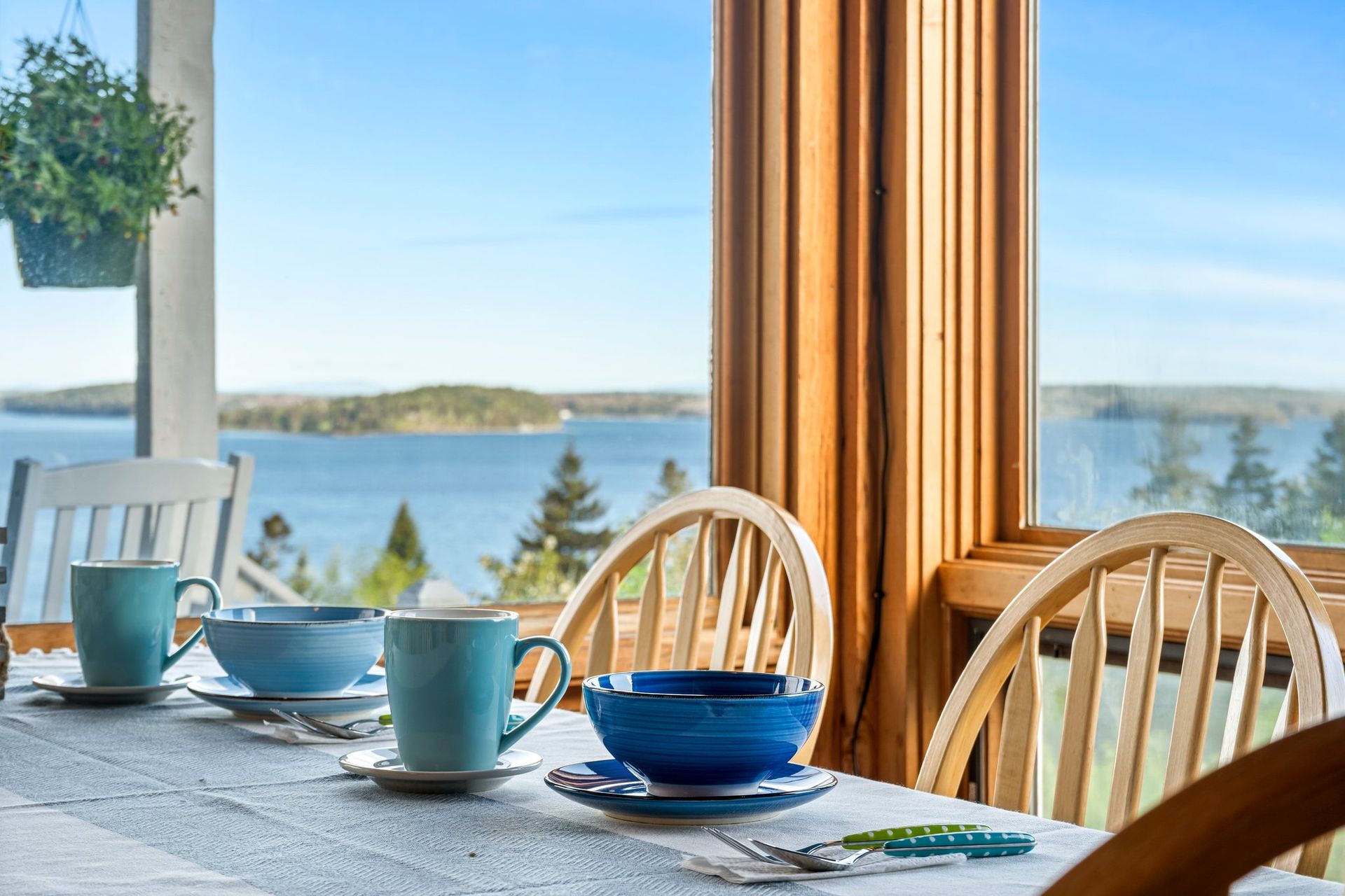 Relax at this dining room table with blue bowls and plates overlooking Frenchman Bay in Gouldsboro Maine.