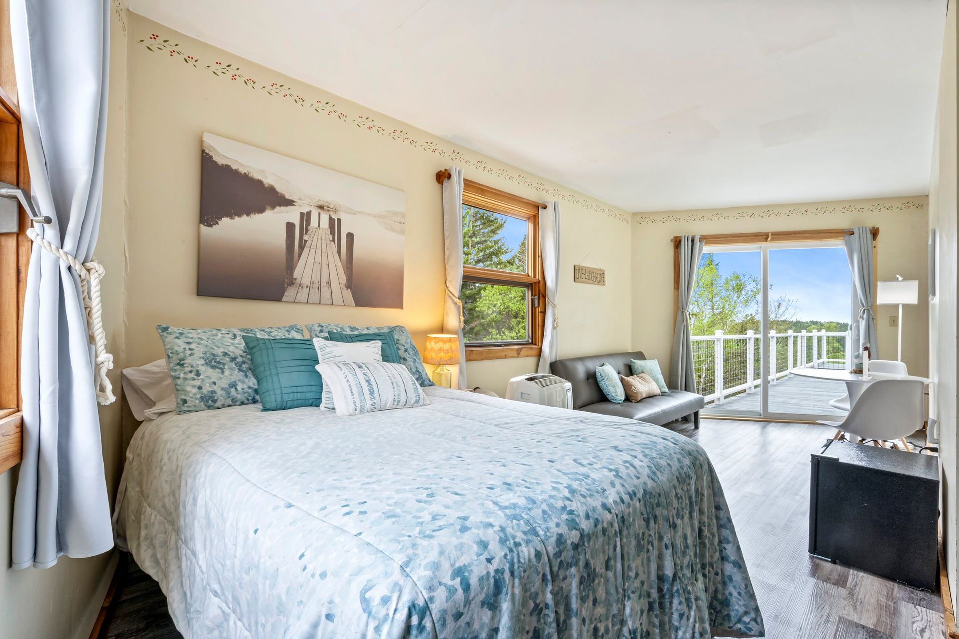 Inn room with a bed, couch, and sliding glass door leading to a balcony with stunning oceanviews.