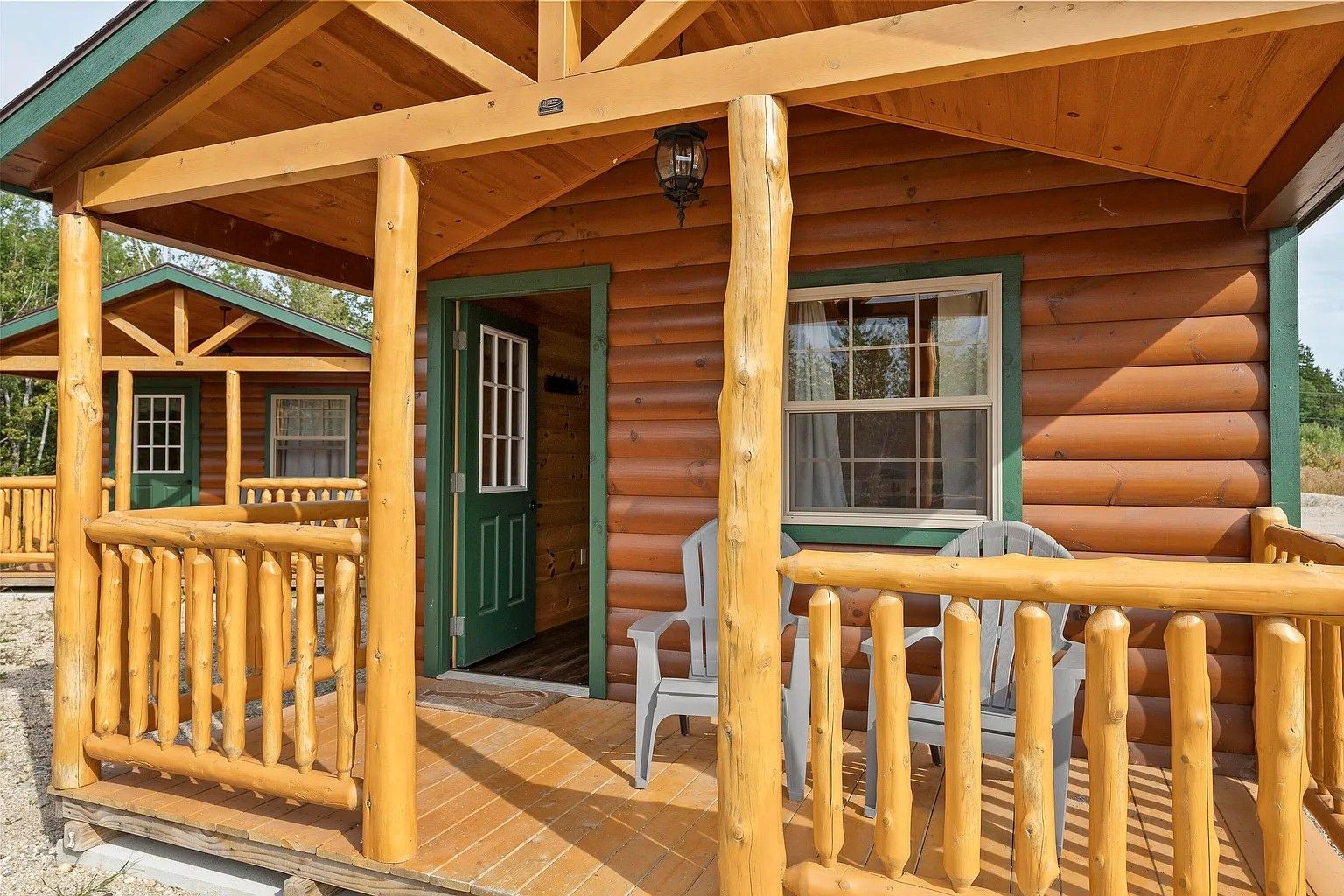 A log cabin with a porch and chairs in front of it.