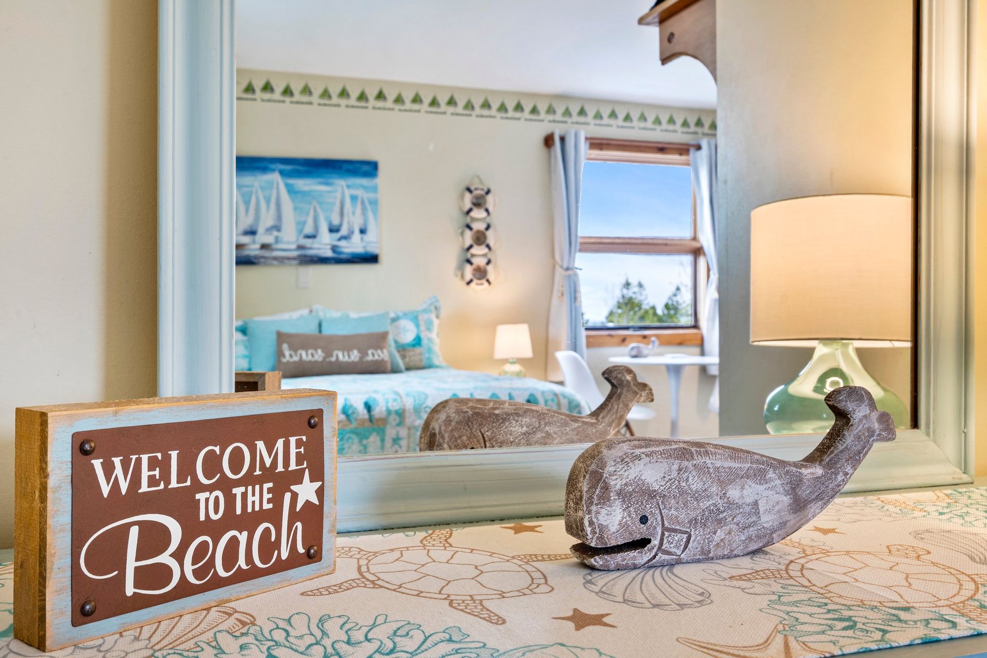 Beach-themed bedroom with turquoise accents and a “Welcome to the Beach” sign on a bed