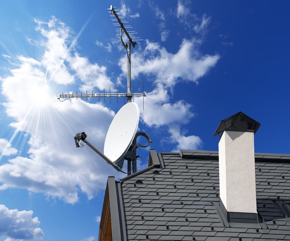 A Satellite Dish On Top Of A Roof With The Sun Shining Through The Clouds — Coastwide Antennas In Wyong, NSW