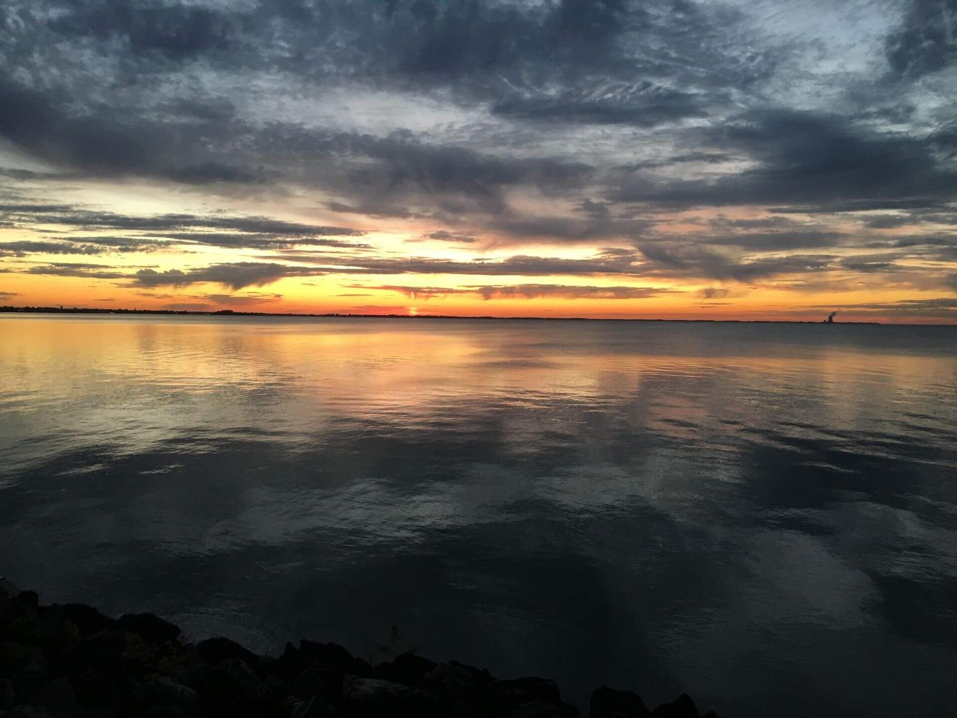 A sunset over Lake Erie with a cloudy sky from the Beach at Scenic Rock Ledge Inn
