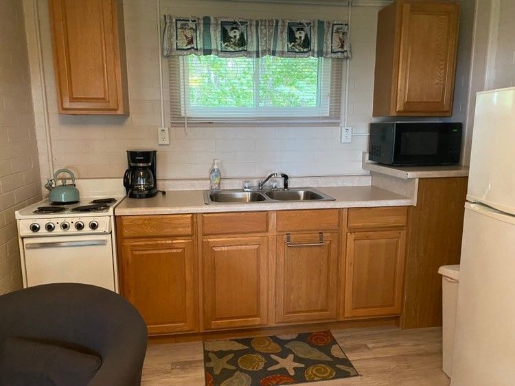 A small kitchen with a sink , stove , microwave and refrigerator.