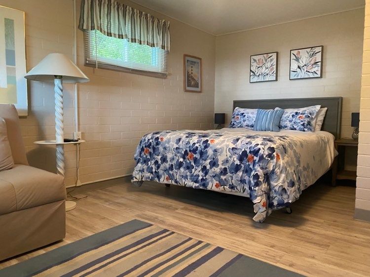 A bedroom with a bed , chair , lamp and window.