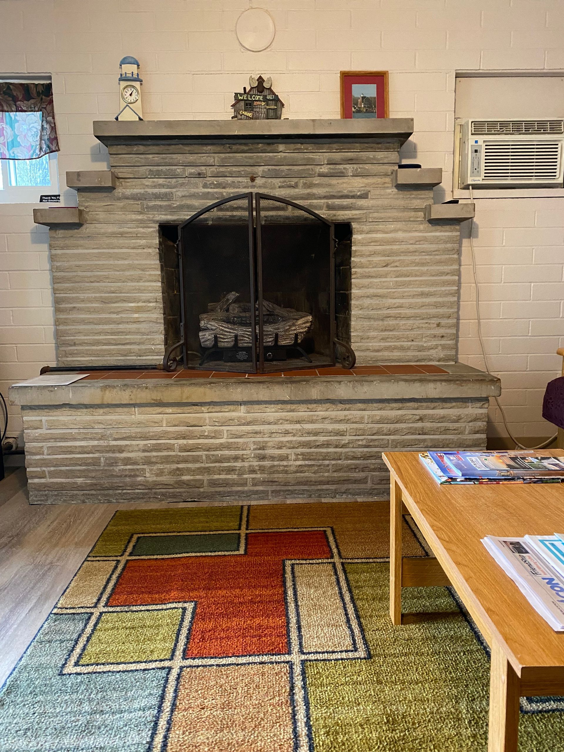 A living room with a fireplace and a rug.