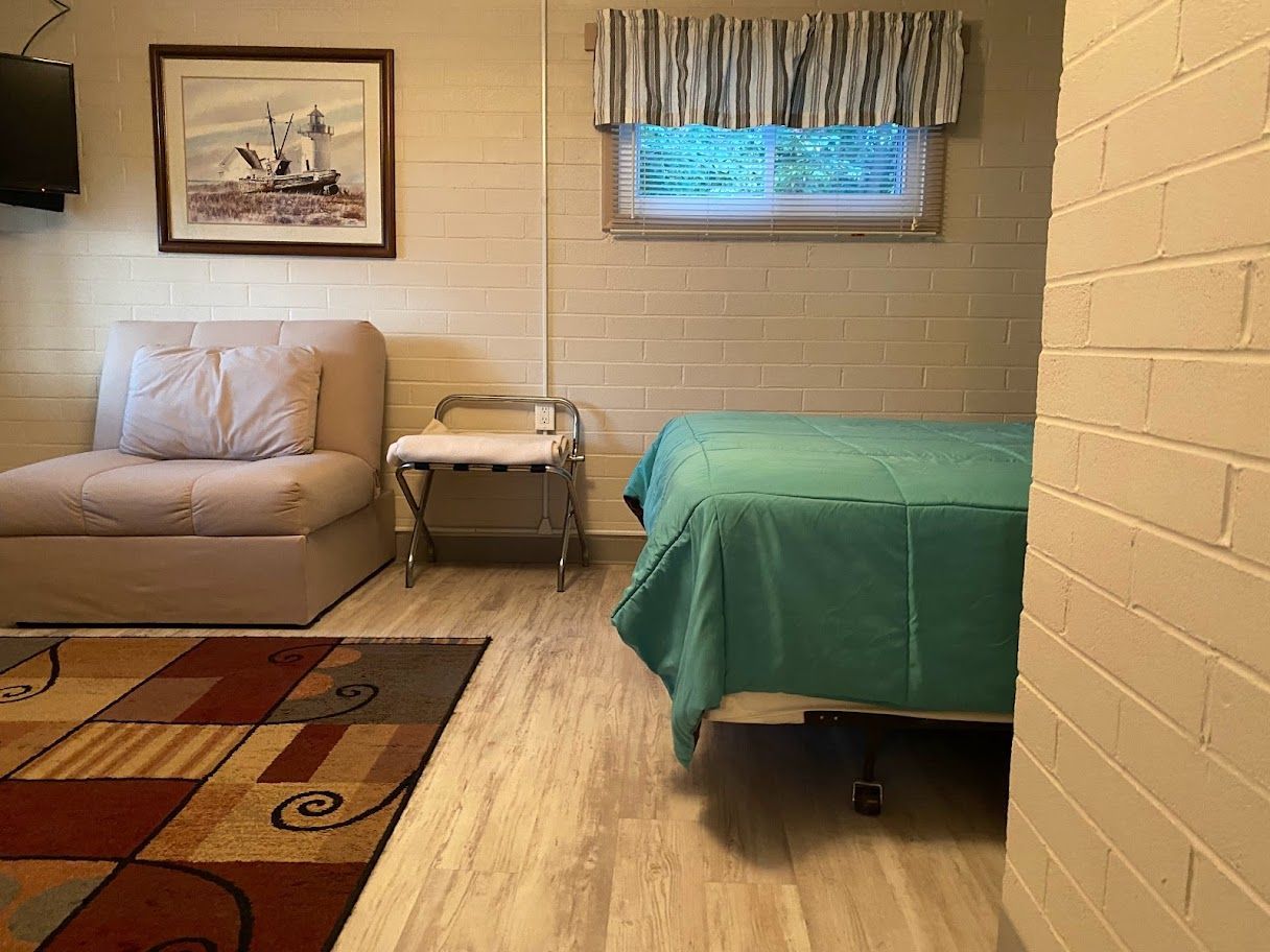 A bedroom with two beds , a chair and a rug.