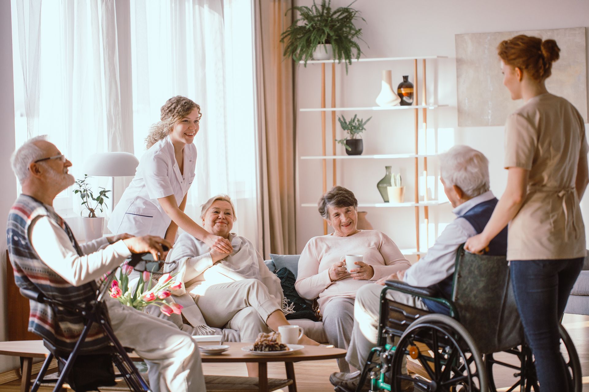 A group of elderly people are sitting around a table in a living room.