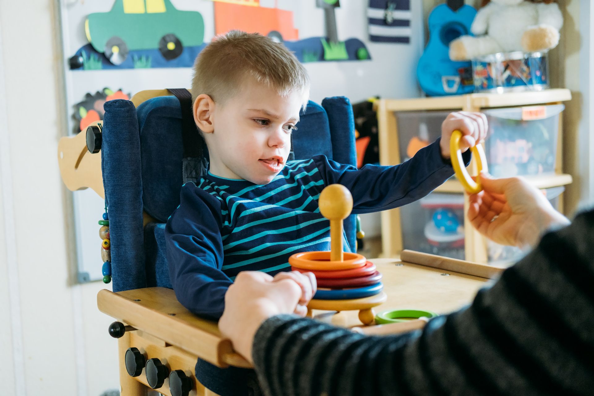 A young boy is sitting in a wheelchair playing with a toy.