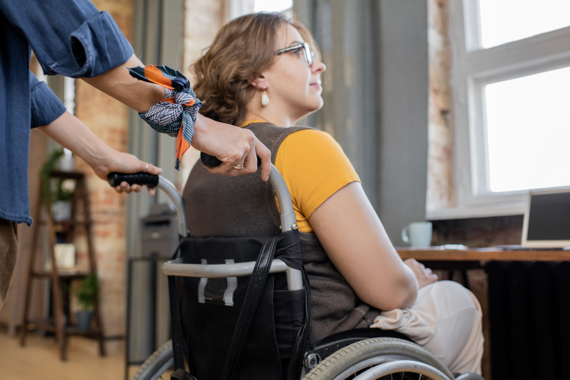 A woman in a wheelchair is being helped by a man.