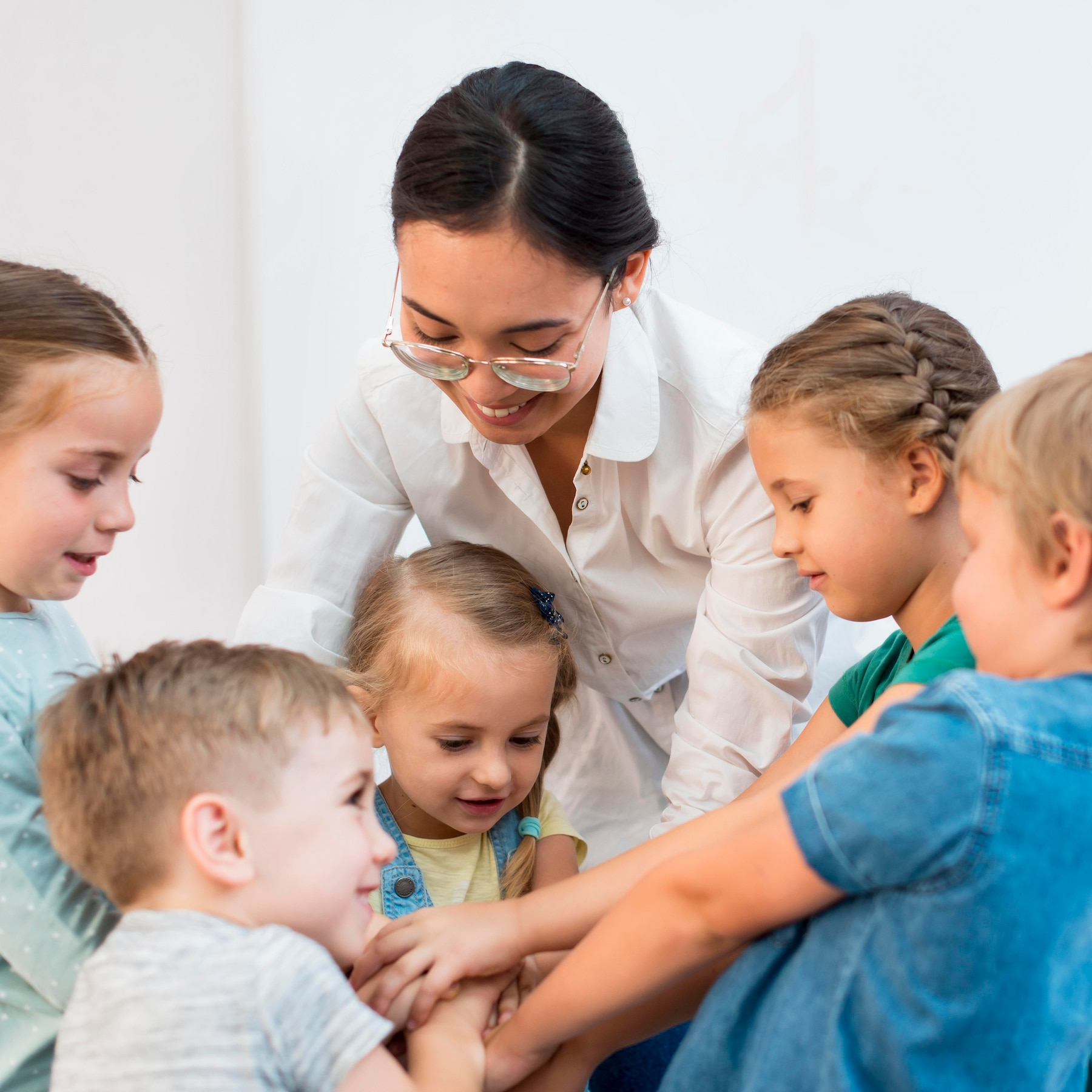 A group of children are sitting in a circle with their hands together