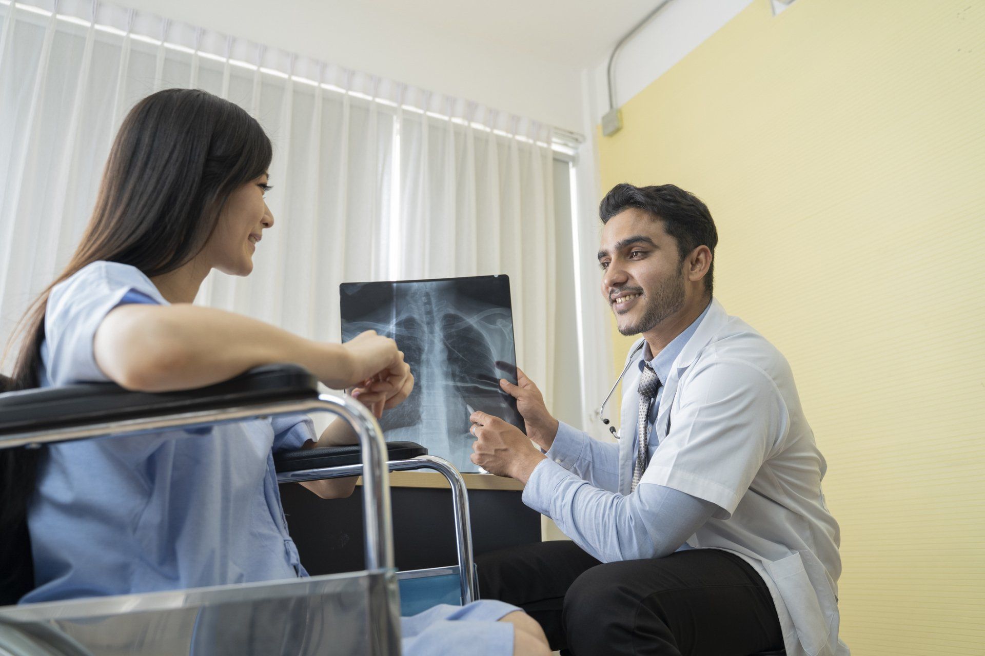 Asian male doctor shows lung x-ray film with female patient — New Hartford, NY — Oxford Medical Imaging Asian male doctor shows lung x-ray film with female patient — New Hartford, NY — Oxford Medical Imaging