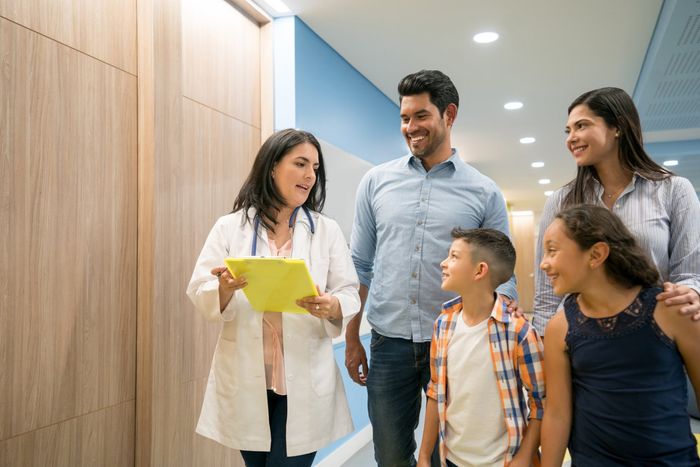 Female doctor talking to patient while his family is listening and smiling — New Hartford, NY — Oxford Medical Imaging