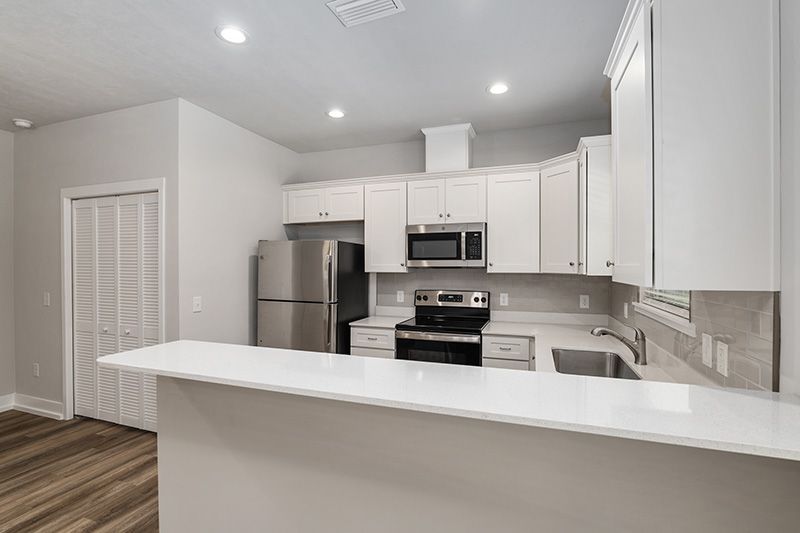 Bright white modern kitchen with stainless steel appliances and a large breakfast bar