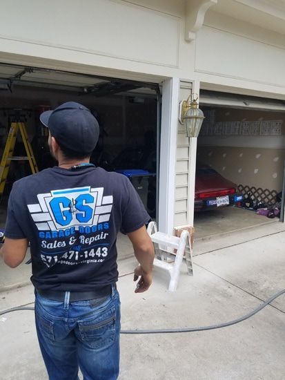 A man wearing a gs shirt is standing in front of a garage door