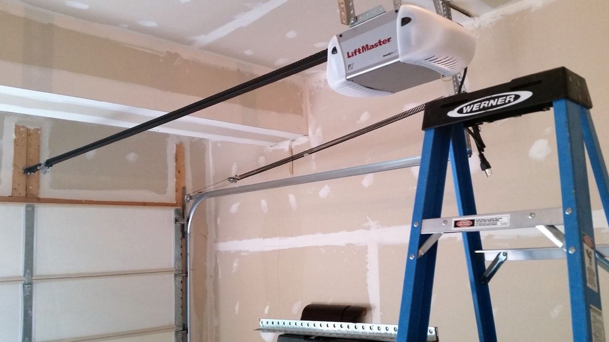 A blue ladder is sitting next to a garage door opener.