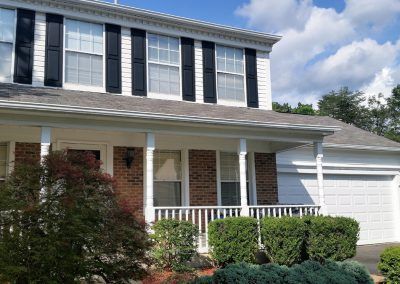A large brick house with black and white shutters on the windows