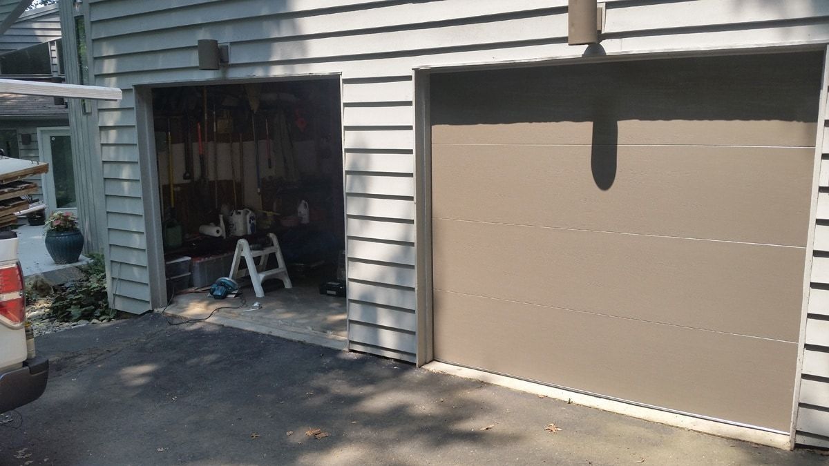 A car is parked in front of a garage door that is open.