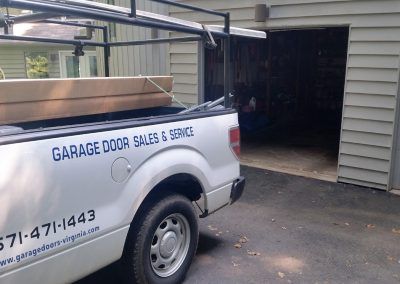 A white truck is parked in front of a garage door