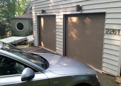 A car is parked in front of a garage with the number 2251 on it