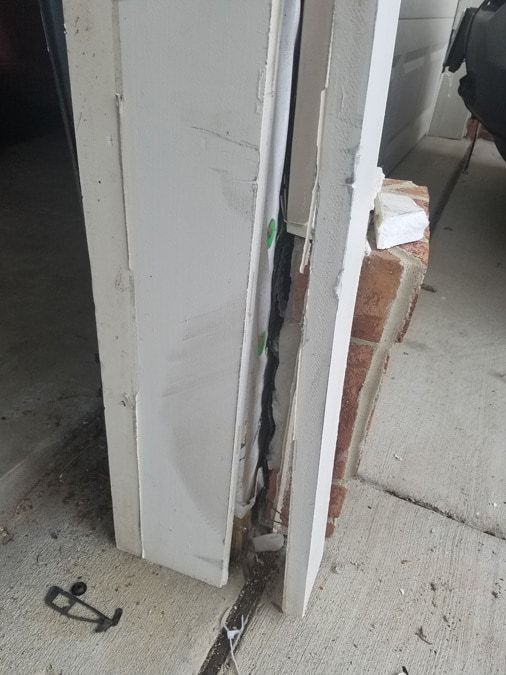 A door with a hole in it is sitting on a sidewalk next to a brick wall.