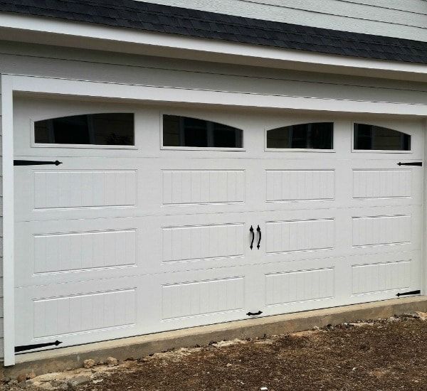 a white garage door with arched windows on a house