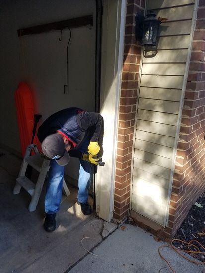 A man is working on a garage door with a drill.