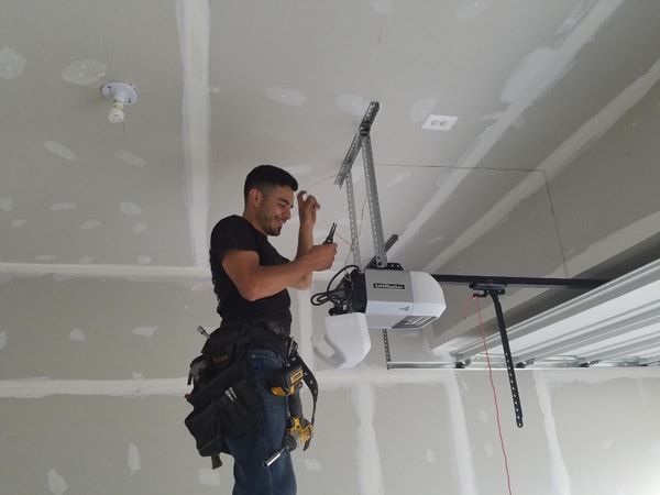 A man is working on a garage door opener in a garage.