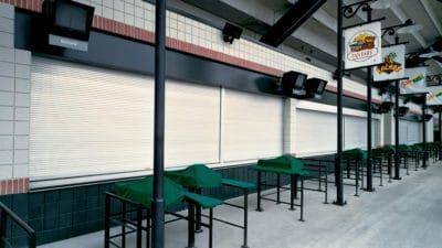 a row of tables and chairs are lined up in front of a building .