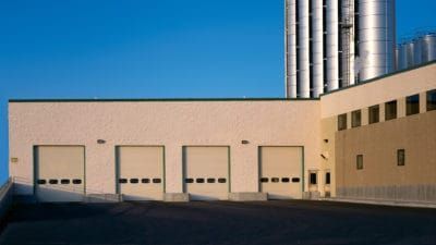 a building with a lot of garage doors and a silo in the background