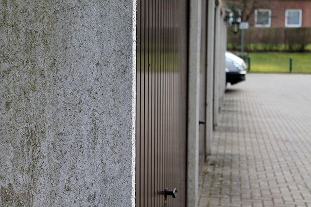 A row of garage doors with a car parked in the background.