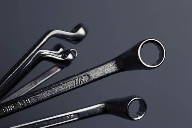 A group of wrenches are stacked on top of each other on a table.