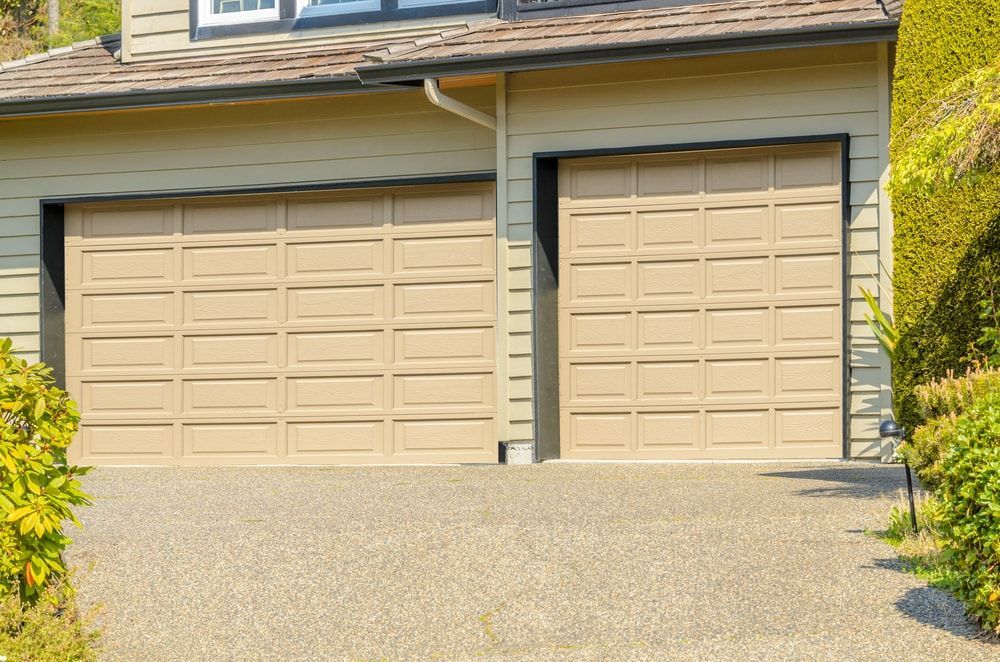 There are two garage doors on the side of a house.